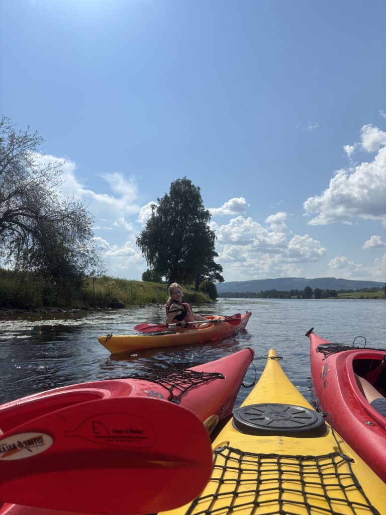 Deltagare paddlar kajak på sjön en solig sommardag